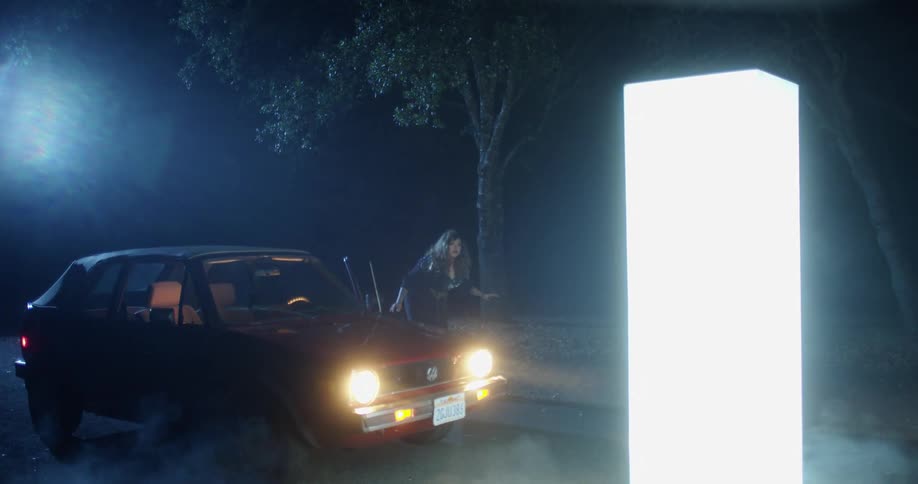 A woman getting out of a car at night