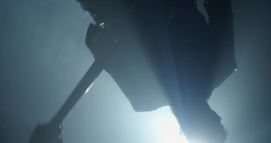 Man wearing glasses plays a guitar as a spotlight shines on him
