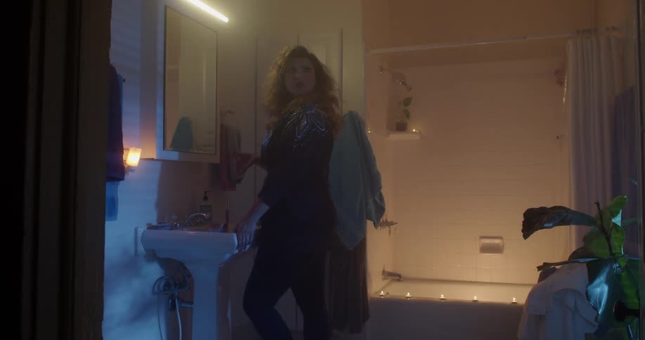 Woman gets something from the bathroom sink and tilts her head back then looks behind her