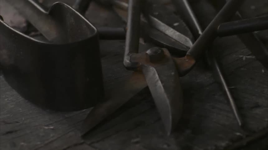 Metal tools are scattered on a workshop table