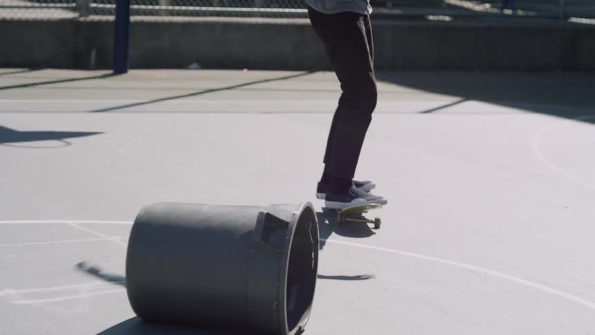 A man jumps over a garbage can with a skateboard