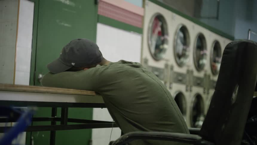 Man lays head on a table at a laundromat