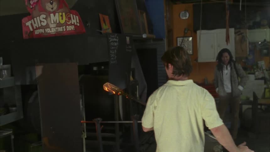 A man moves a hot glass jar from the fire