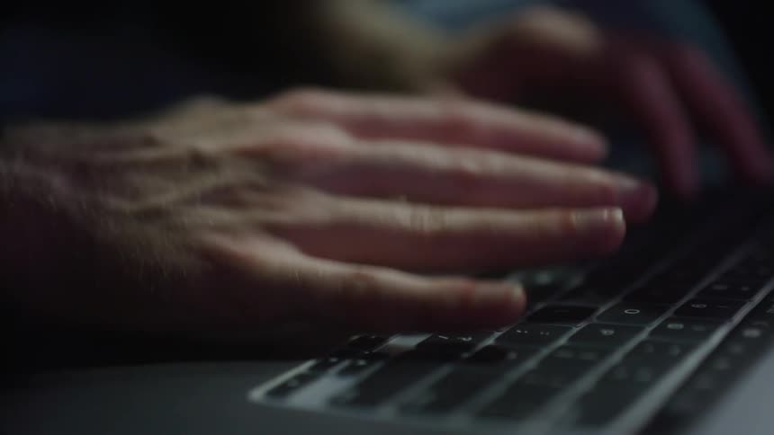 A man types on a laptop keyboard