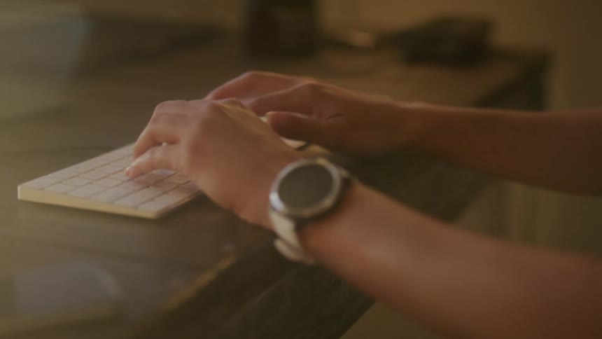 A woman types on a wireless keyboard at her desk