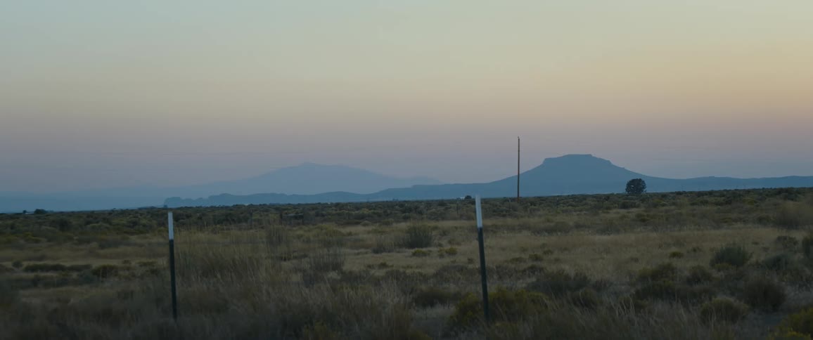 A field of grass in a rural area is displayed at dusk