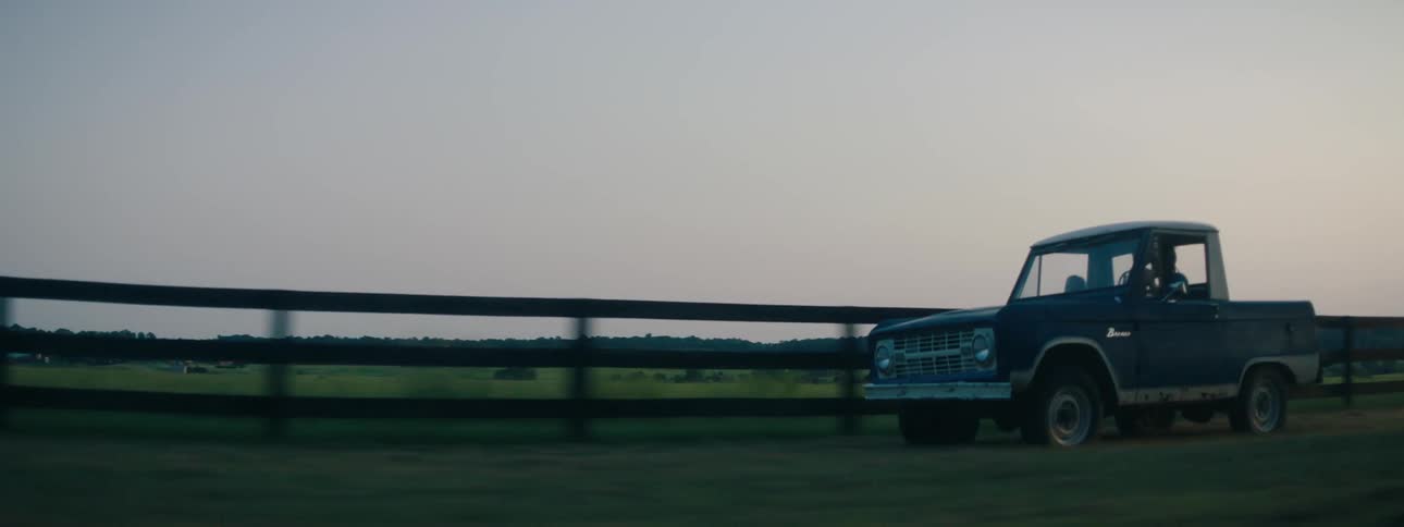 Vintage small pickup truck driving on a rural road at evening