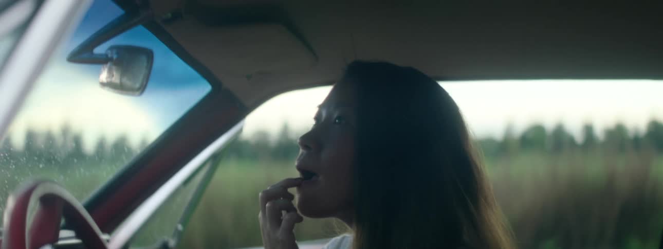 A woman is in a parked car in a rural area