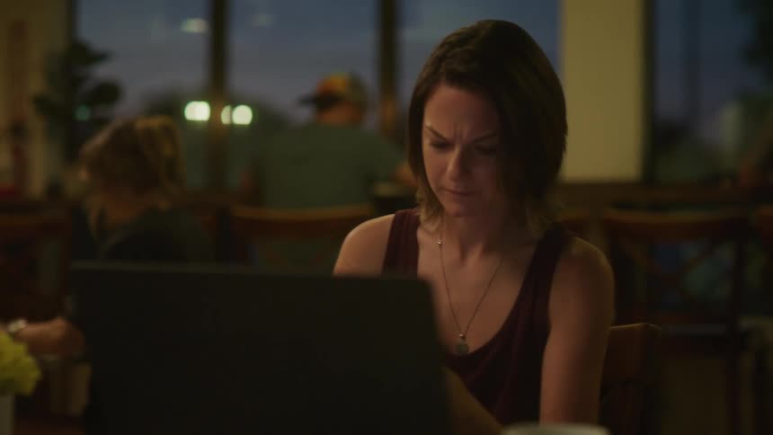 A woman is using a laptop and talking on her cell phone in the restaurant