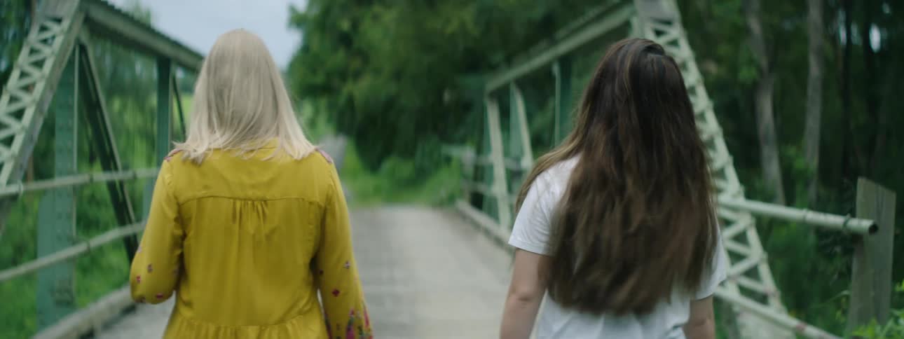Two women walk across the bridge together