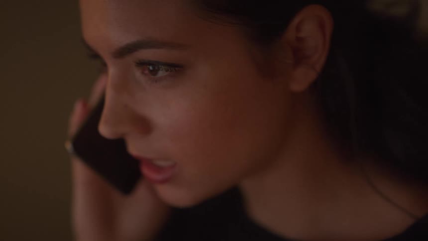 A young woman shakes her head as she speaks with someone on her cell phone