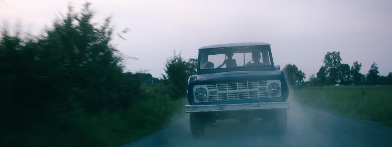 The silhouette of a driver and children in a truck traveling on a dirt road