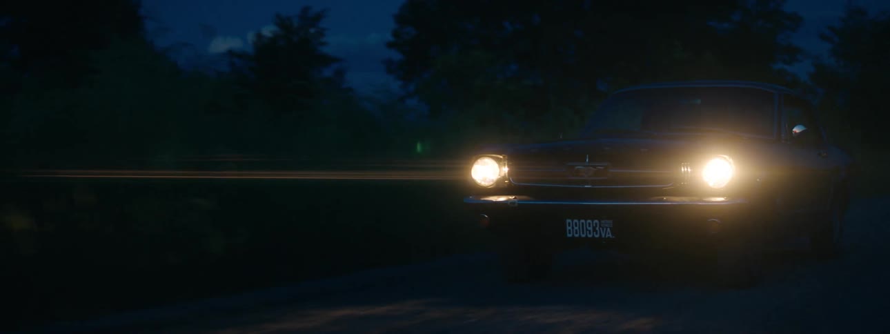 An antique car traveling on a road at night
