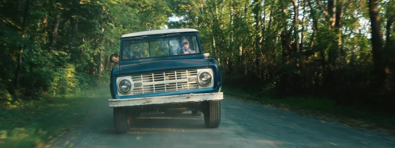 A person is driving a truck down a dirt road in spring