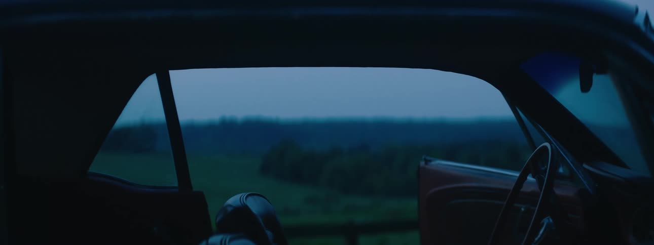 A car parked with its door open in a field at night