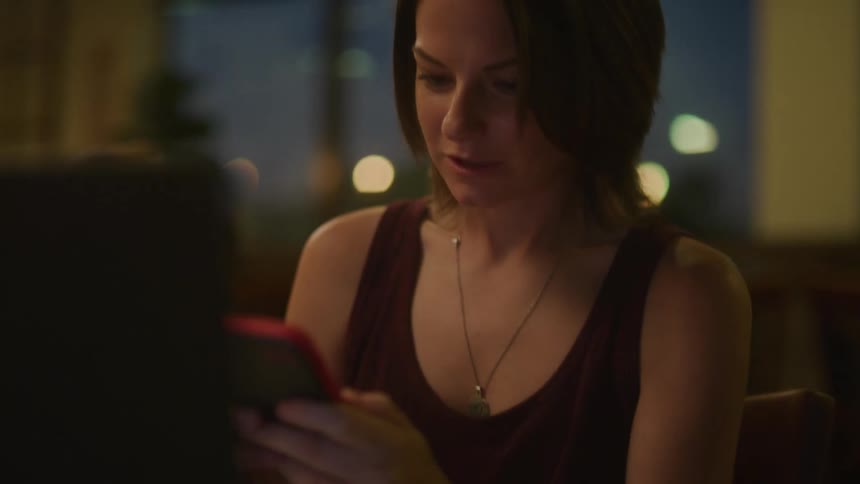A woman answers the phone while using her computer