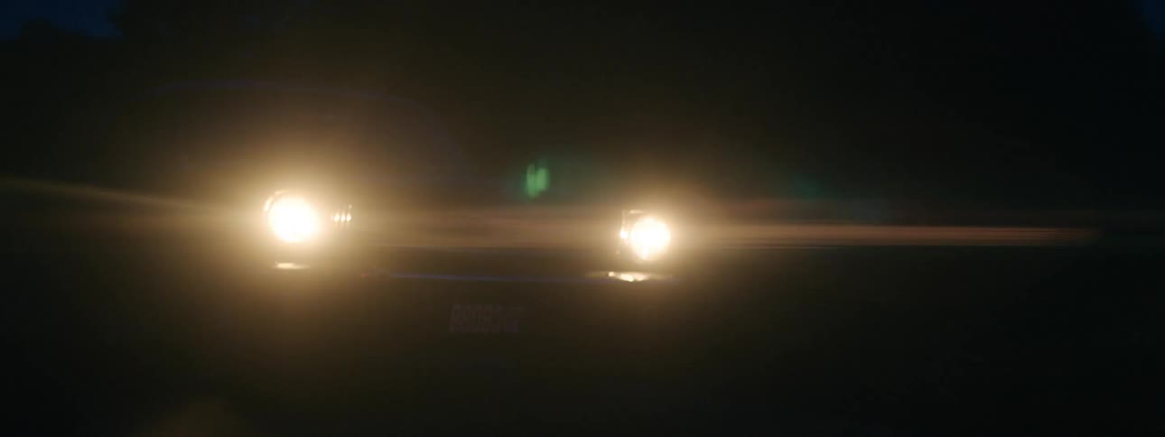 Pickup truck with headlights on driving on a rural road at night