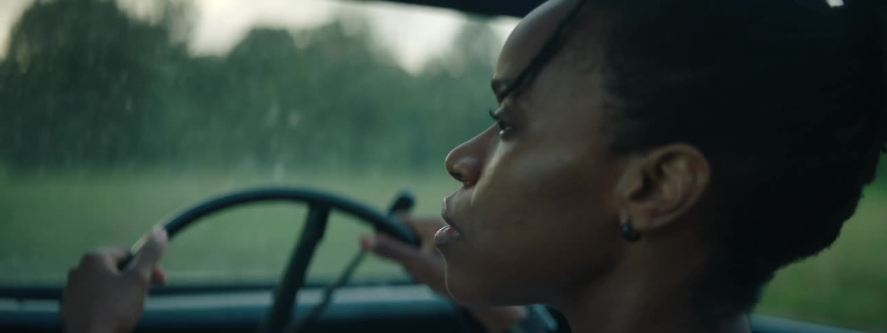Young woman driving a convertible car on a dirt road in the countryside at morning