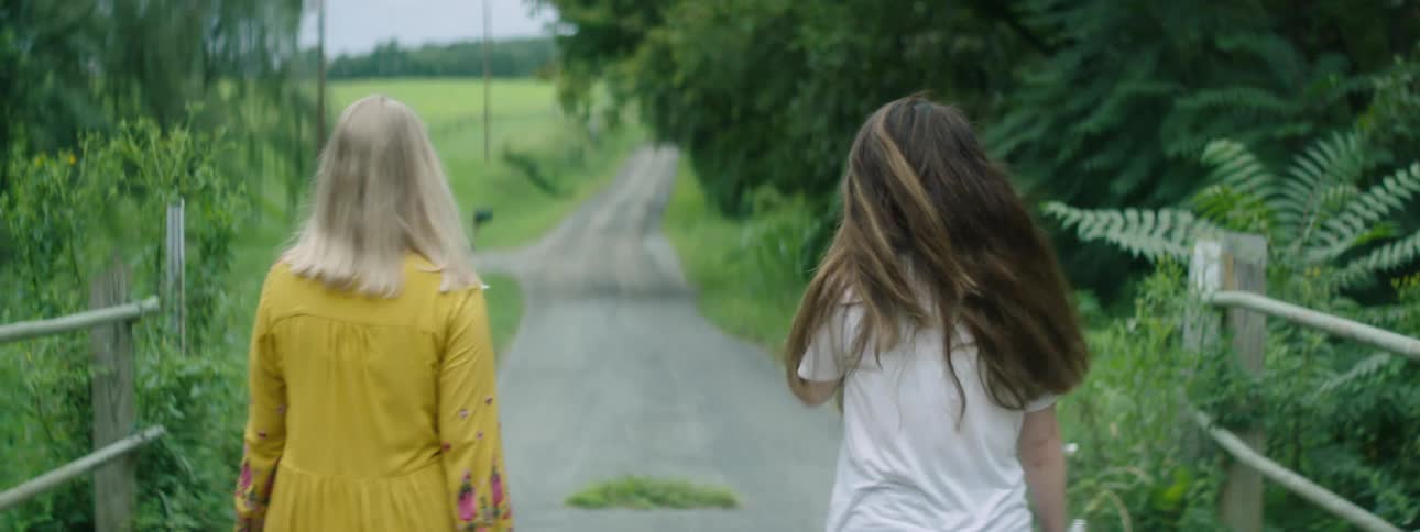 Young female friends walking over a bridge in the countryside