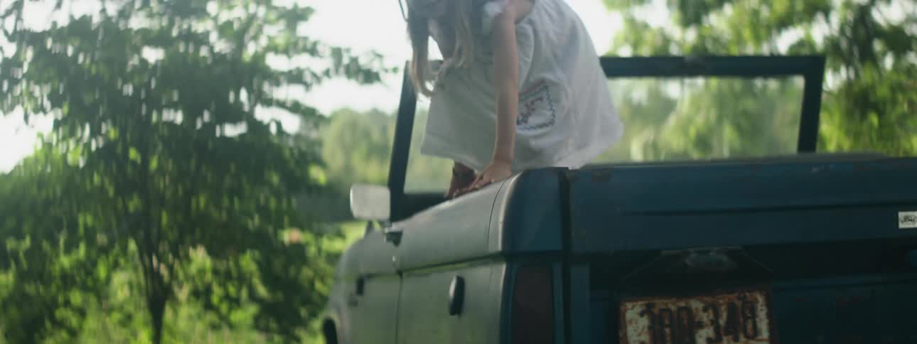A child jumps from the car and lands in the grass