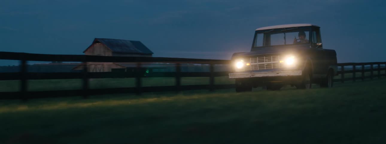 A pickup truck drives past the farm land