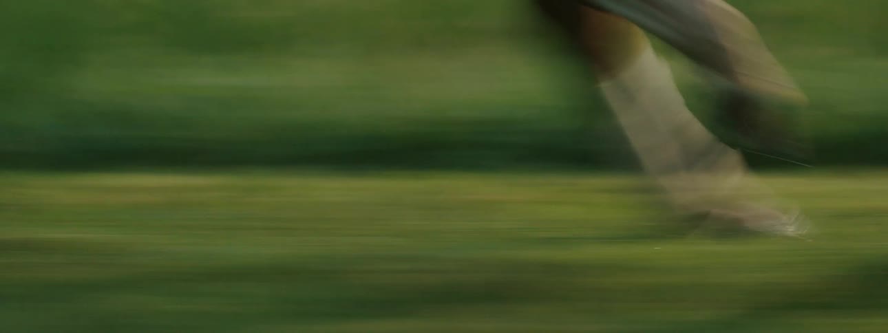 A horse gallops swiftly along a grassy field with a rider on its back