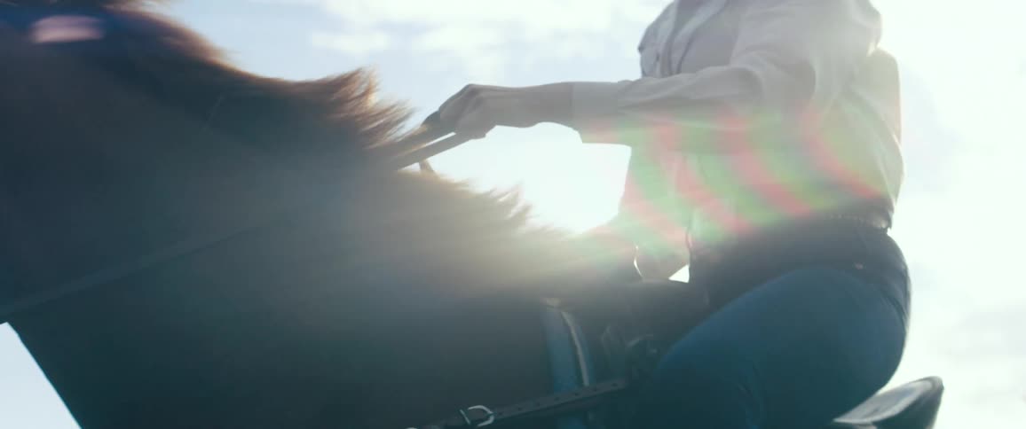 A woman leans back while riding on her horse