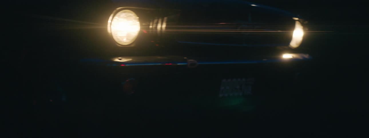 A car travels through a field with its headlights at night