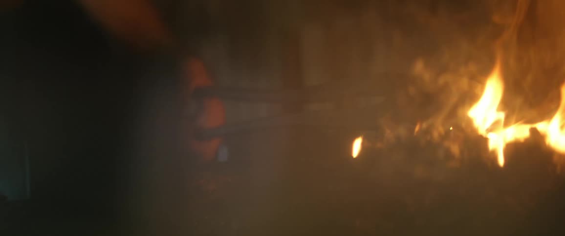 A blacksmith is heating metal on the coal fire