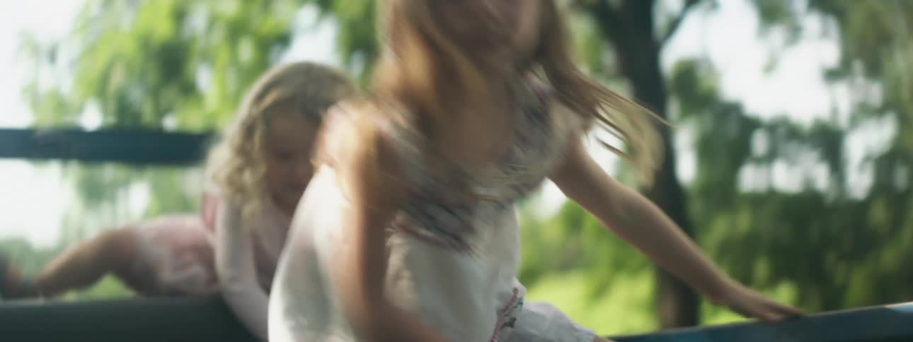 Two little blonde girls with white dresses climb and jump out of pickup truck in the countryside
