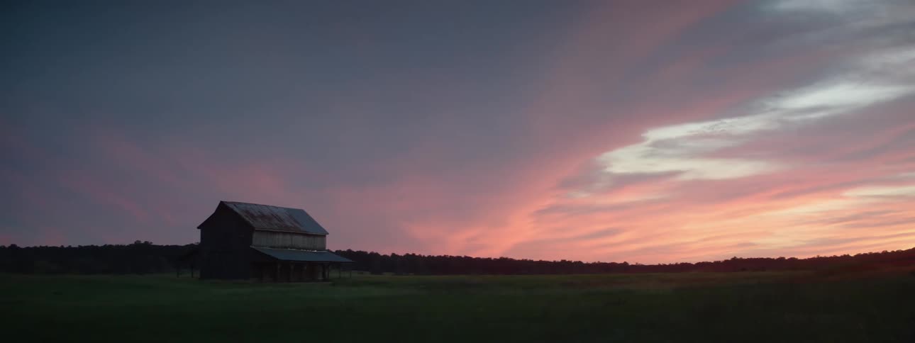 A rural barn at sunset on a cloudy day