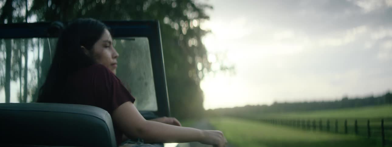 A woman riding in a convertible with her arm hanging over the side