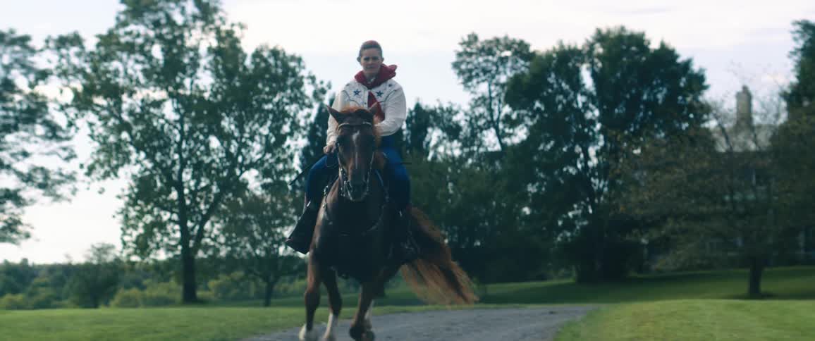 A woman rides a horse on a gravel trail