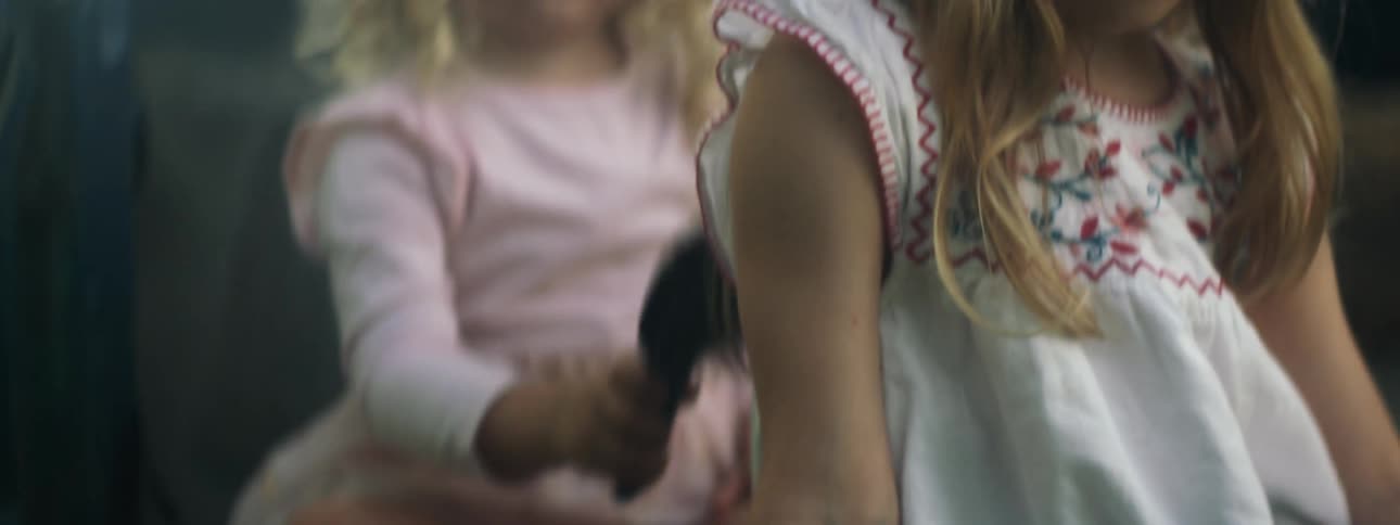 Older sister smiles as younger sister brushes her hair