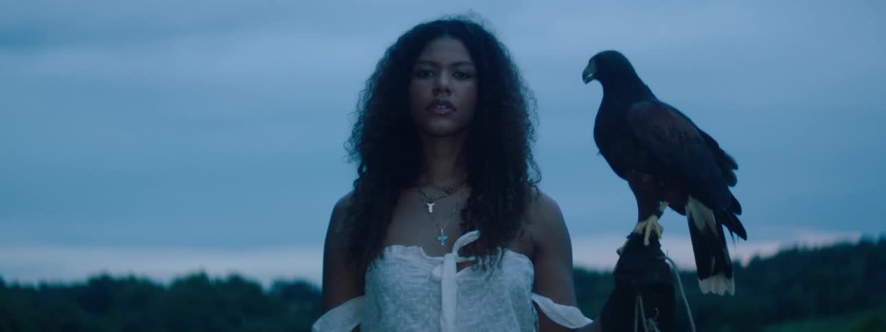 A woman standing with a crow