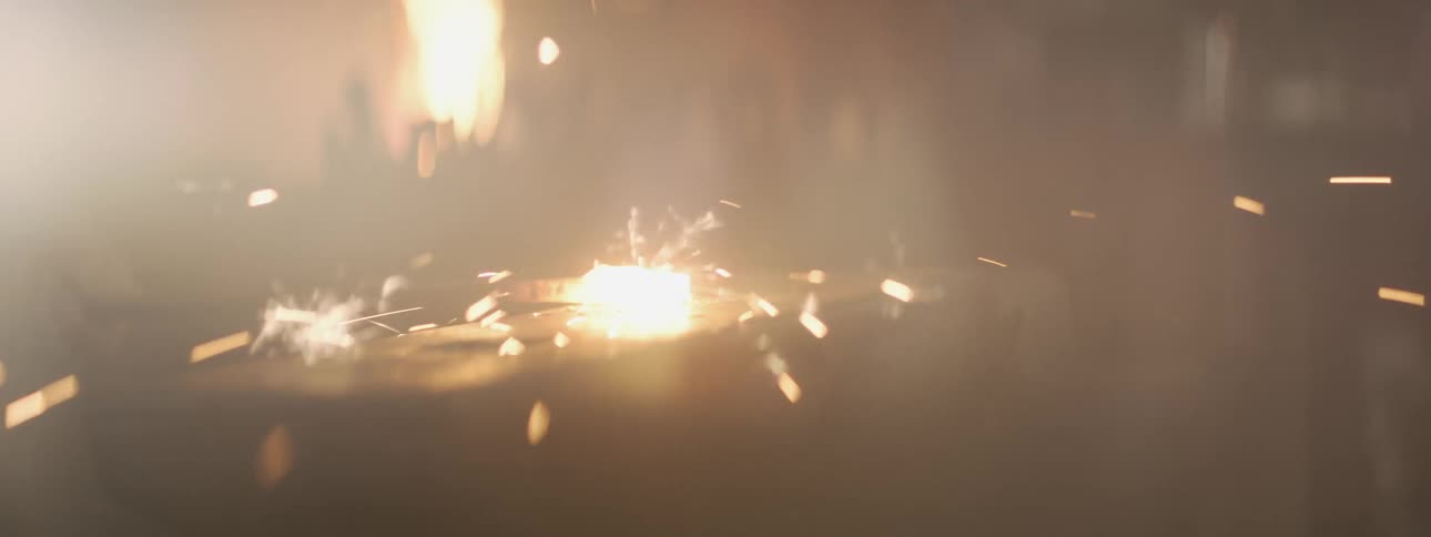A female blacksmith takes metal from the fire to hammer