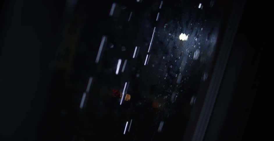 Rain falling in front of a window at night
