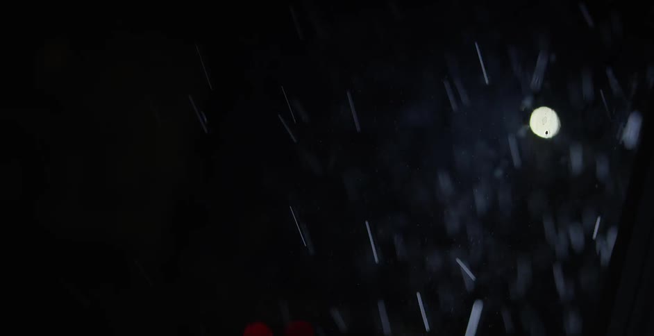 Rain falling in front of a light at night