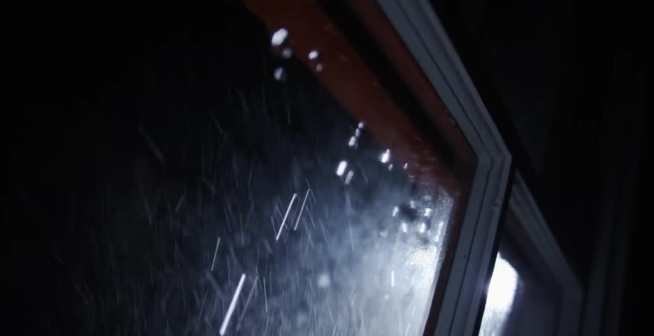 Water is pouring on a window outside at night