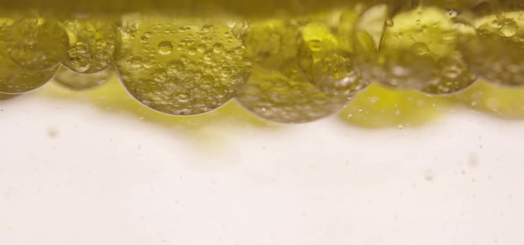 Yellow bubbles float at the surface of clear liquid
