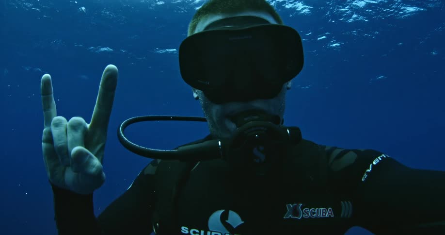 A diver flashes a rock on hand signal in the ocean