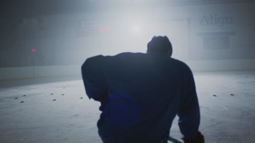 Hockey player kneels in a dimly lit rink