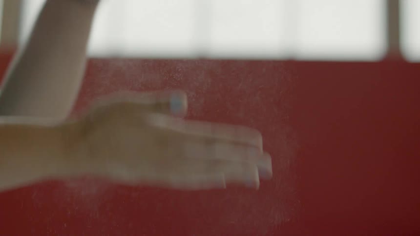 Two hands wipe white dust together in a large room
