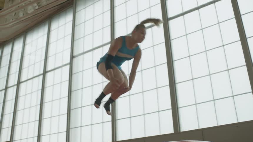 A woman does a jump and flip in a gym