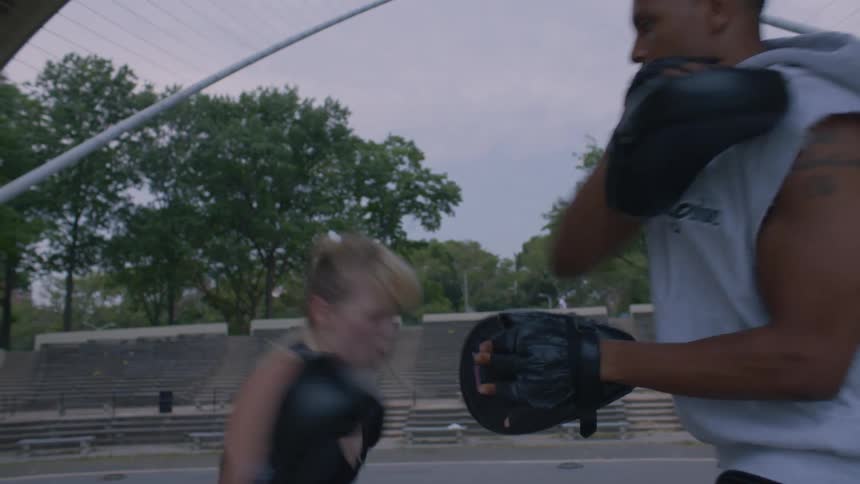 Two people are boxing outside on a cloudy day