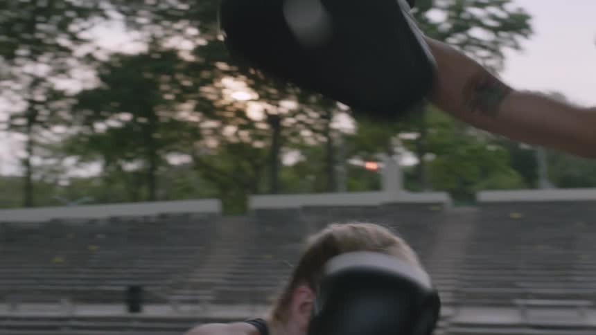 A woman is sparring with a man outside on a cloudy day