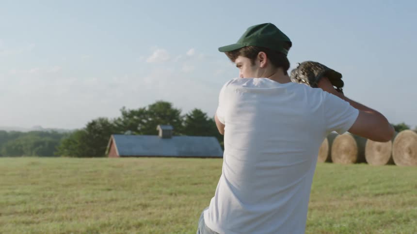 A man standing on a field throws a baseball on a sunny day