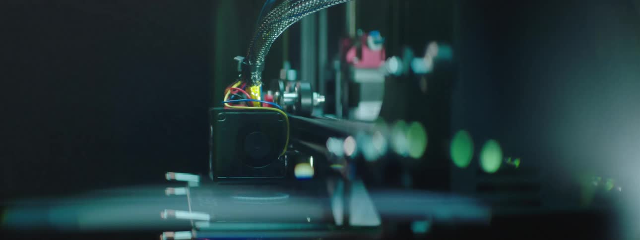 3d printer arm moves forming shape as light shines from one side of printer