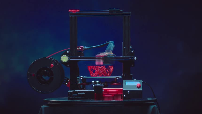 3d printer builds up shape as material flows from rotating spool