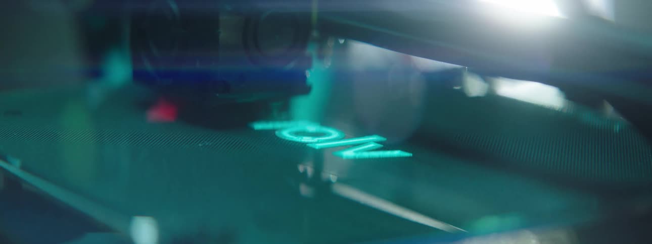 A machine with a laser printing a logo on a sheet of plastic